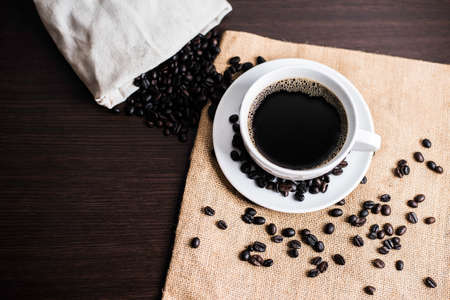 Black coffee in white cup and coffee bean on wood table background.の写真素材
