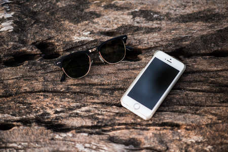 Smartphone style white and sunglasses on wood background.の写真素材