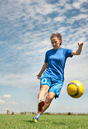 young girl kicking soccer ball on fieldの写真素材