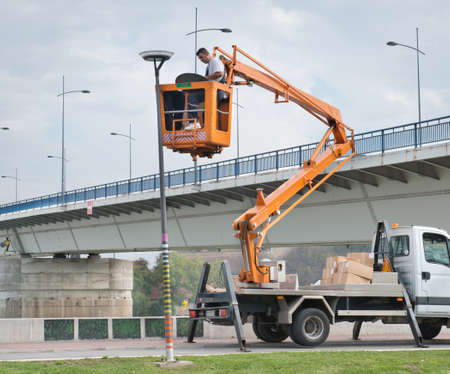 Street light repairs man standing on a yellow crane
