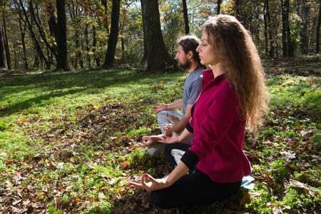 girl and man doing yoga meditation in a forestの写真素材
