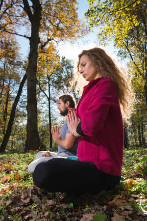 girl and man doing yoga meditation in a forestの写真素材