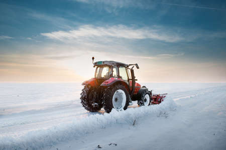 Tractor cleaning snow in sunsetの写真素材