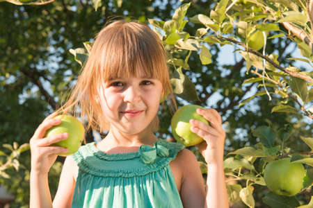 Happiness girl picking an apple from a treeの写真素材