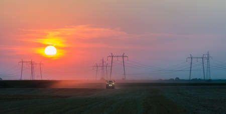 tractor plowing field at duskの写真素材