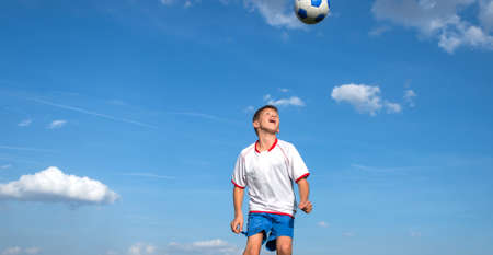 happy boy playing football on sky backgroundの写真素材