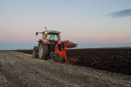 Tractor plowing at sunset