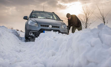 man digging up stuck in snow carの写真素材