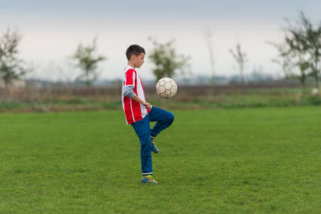 Boy kicking football with his legの写真素材
