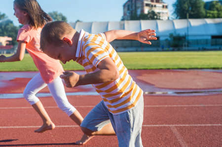 Happy girl and boy run on the trackの写真素材