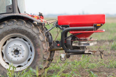 Tractor and fertilizer spreader in fieldの写真素材