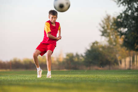 kid kicking a soccer ball on the fieldの写真素材