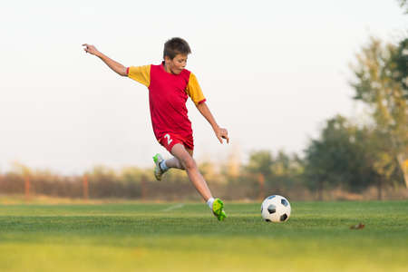kid kicking a soccer ball on the fieldの写真素材