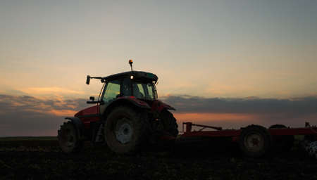tractor plowing a field at dusk