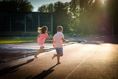 Happy girl and boy run on the trackの写真素材