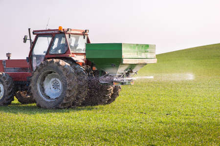 Tractor and fertilizer spreader in fieldの写真素材