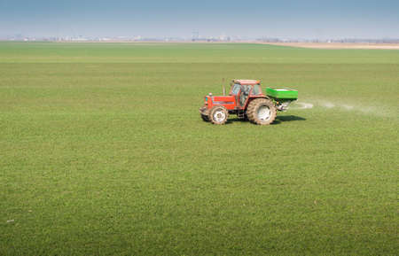 Tractor and fertilizer spreader in fieldの写真素材