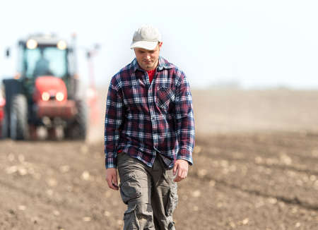young farmer on farmland with tractor in backgroundの写真素材