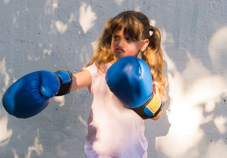 Little girl wearing blue boxing glovesの写真素材