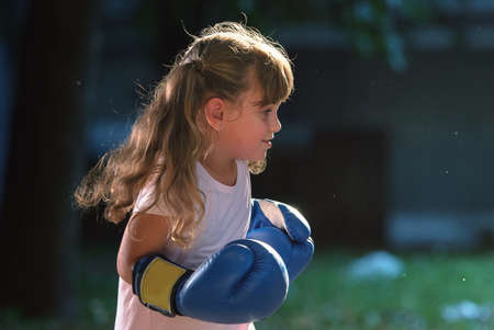 Little girl wearing blue boxing glovesの写真素材