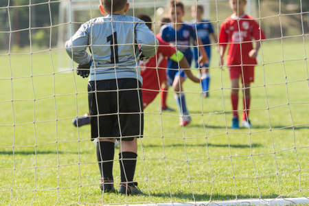 Young boys playing football soccer game on sports fieldの写真素材
