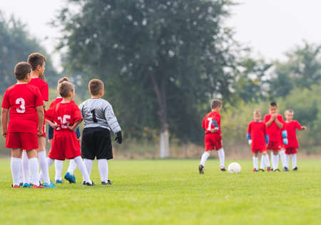 Young boys playing football soccer game on sports fieldの写真素材