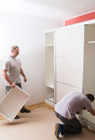 Furniture maker sets wardrobe in bedroomの写真素材