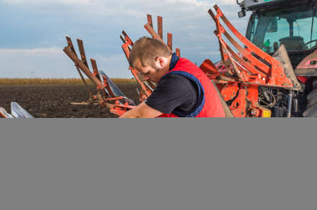 Young mechanic fixing plow on the tractorの写真素材