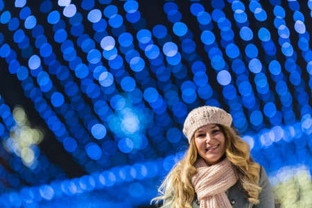 Young happy pretty woman walking at night with christmas decorations. の写真素材