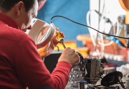 Young man with safety glasses repairing motheboard with soldering ironの写真素材
