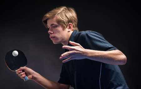 young man tennis player in play on black backgroundの写真素材