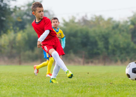 Boy kicking soccer ball on sports fieldの写真素材
