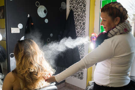  Hairdresser applying hair spray on ombre hair in beauty salonの写真素材