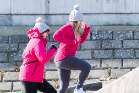 Mother and daughter wearing sportswear and running on windy day at quayの写真素材