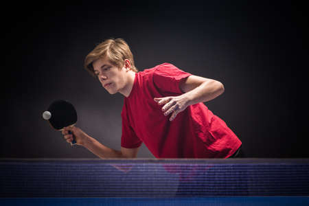 young man tennis player in play on black backgroundの写真素材