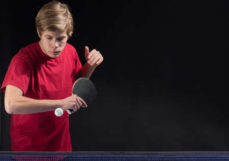 young man tennis player in play on black backgroundの写真素材