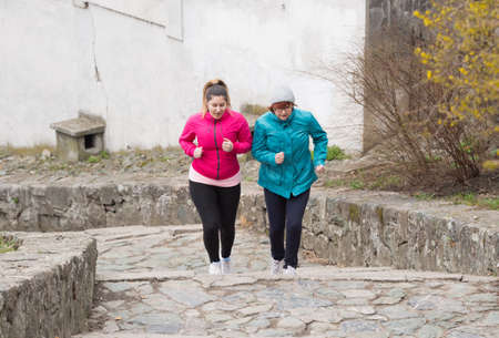 Mother and daughter wearing sportswears and running upstairs at city fortressの写真素材
