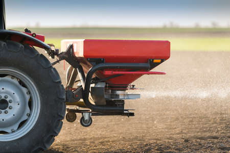Tractor spreading artificial fertilizers  in field