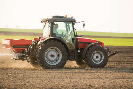 Tractor spreading artificial fertilizers  in field