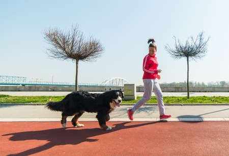 Young pretty girl running outdoor in the spring with her Bernese Mountain dogの写真素材