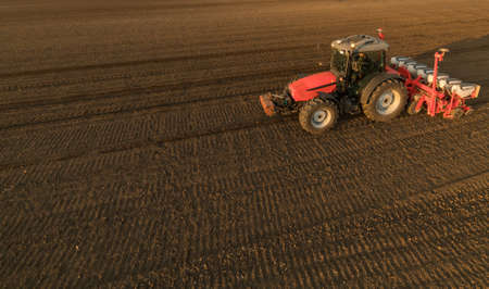 Farmer with tractor seeding - sowing crops at agricultural fields in springの写真素材