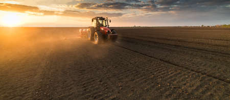 Farmer with tractor seeding - sowing crops at agricultural fields in springの写真素材