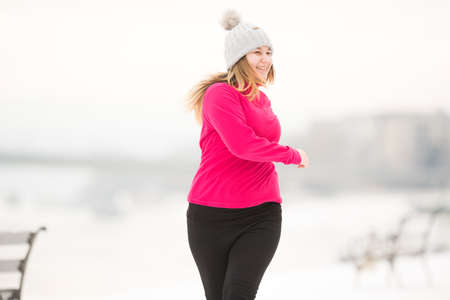 Pretty young girl wearing sportswear and running on snow during winter timeの写真素材