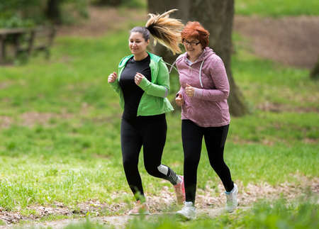Mother and daughter wearing sportswear and running in green forest at mountainduring springの写真素材