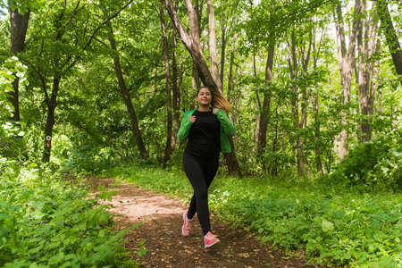Pretty girl wearing sportswear and running in forest at mountain during springの写真素材