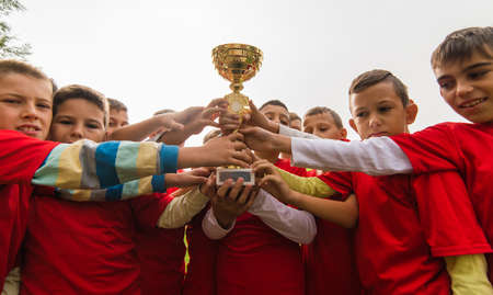Kids soccer football - young children players celebrating with a trophy after match on soccer fieldのeditorial素材