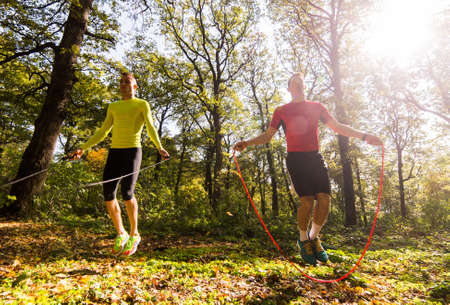 Handsome young men wearing sportswear and exercising in forest at mountain during autumnの写真素材