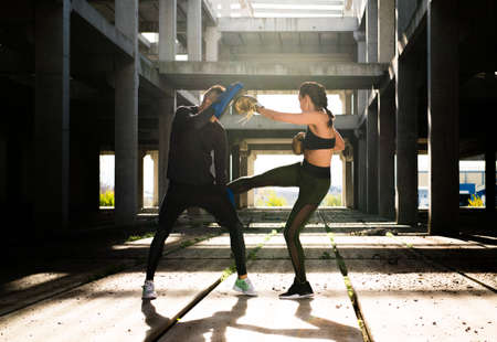 Young athlete couple doing kick boxing exercise in an old abandoned building の写真素材
