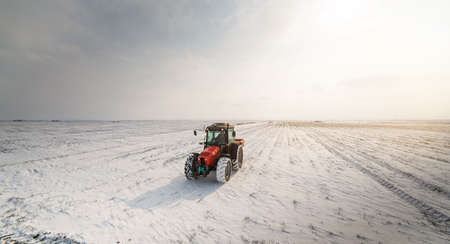 Farmer with tractor seeding - sowing crops at agricultural fields in winter - snowの写真素材