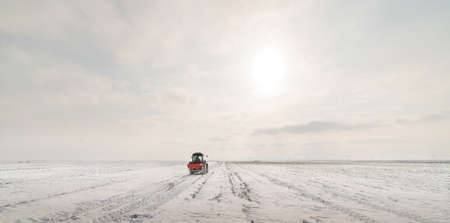 Farmer with tractor seeding - sowing crops at agricultural fields in winter - snowの写真素材